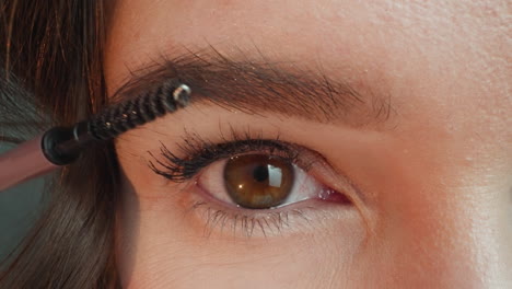 woman combs thick eyebrows with brush to make good shape