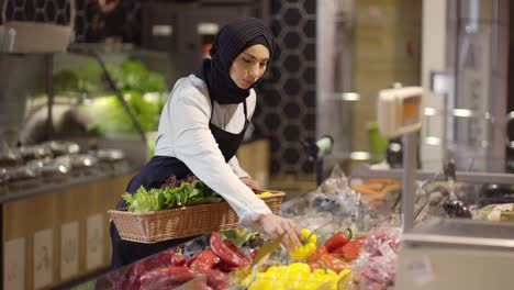 Muslimische-Frau-In-Schürze-Füllt-Das-Frische-Gemüse-Im-Supermarkt-Nach