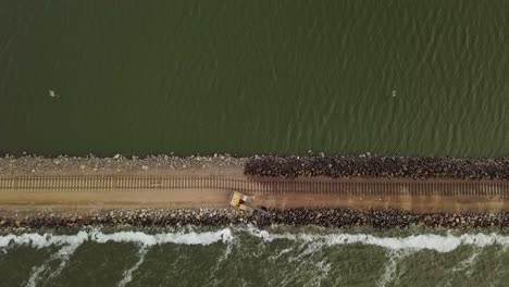 Rising-overhead-aerial-of-railroad-construction-by-water-in-Argentina