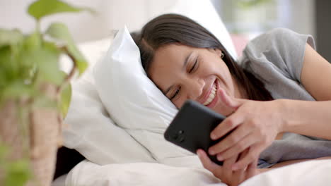 lying in bed, teenage girl smiling while using smartphone, enjoying leisure time