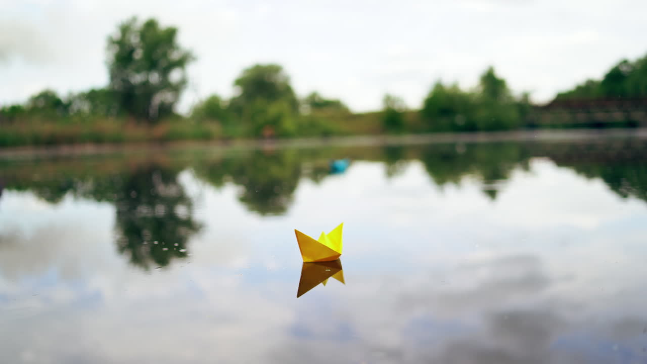 Paper boat sailing on blue water surface. Simple small origami paper boat floating quietly in blue clear river