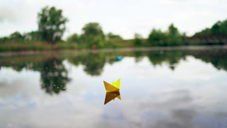 paper boat sailing on blue water surface. simple small origami paper boat floating quietly in blue clear river
