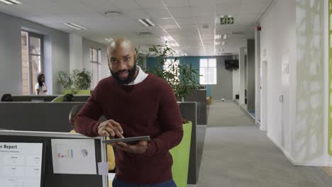 Portrait-of-happy-african-american-businessman-using-tablet-standing-in-office,-slow-motion