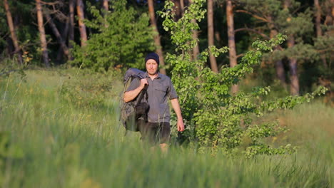 hiker descending on a hill. hiker with backpack descending from the forest