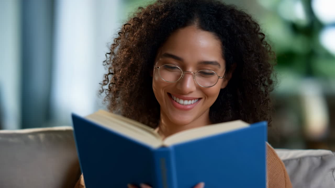 Jeune femme heureuse aux cheveux bouclés lisant un livre