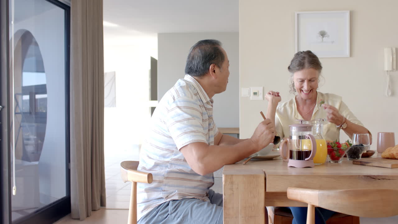 Eating breakfast together, senior couple enjoying morning meal at dining table
