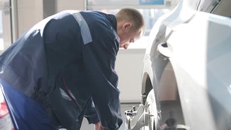 mechanic performing a wheel alignment process in a modern workshop. professional equipment is used to ensure accurate vehicle alignment for optimal performance and safety