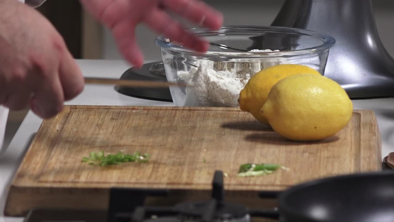 Chef skillfully chops herbs and zests lemons in a contemporary kitchen, showcasing techniques for enhancing the flavor of the dish. Fresh ingredients are the focus of this culinary moment