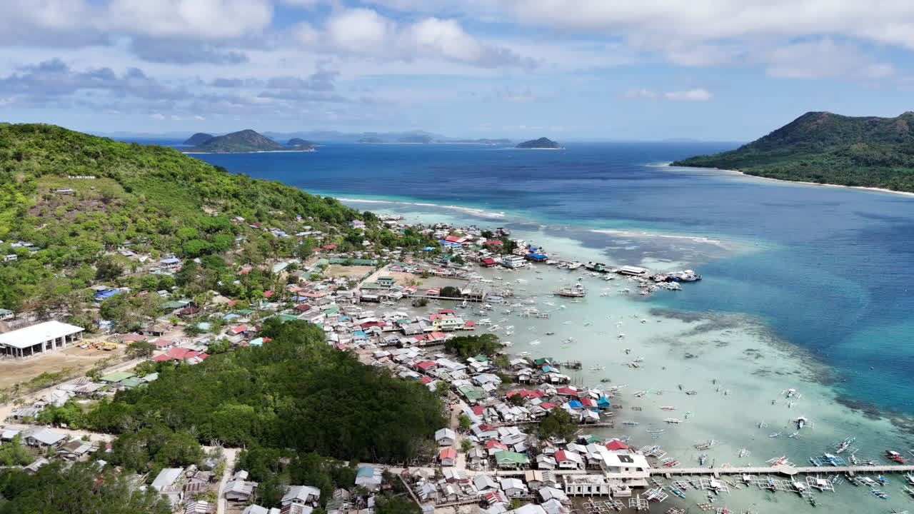Ripresa aerea con drone di Linapacan centro che mostra una comunità costiera accanto ad acque turchesi con l'isola di Patoyo in primo piano.