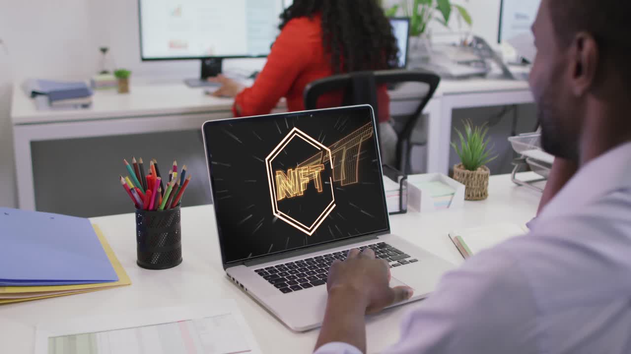 Video of african american man working on laptop with nft on screen
