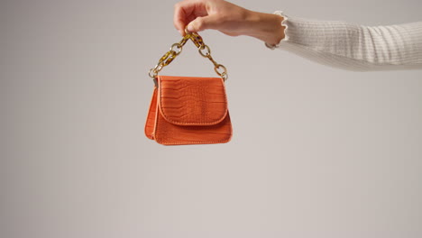 primer plano de una mujer influyente en las redes sociales produciendo contenido generado por el usuario sosteniendo un bolso de moda naranja 3