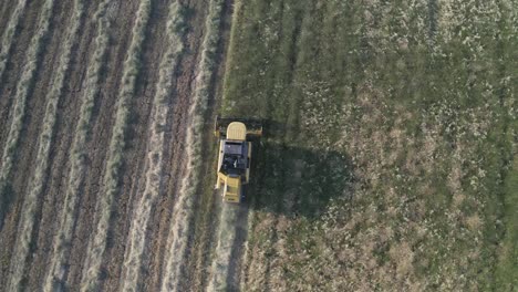 aerial view of a farmer on a tractor with a full trailer of bales of straw.