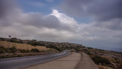 The-road-to-Blue-Wall-and-Grotto-Viewpoint-makes-an-incredible-view-under-the-fast-moving-clouds-and-people-by-the-time-laps-view,-Malta