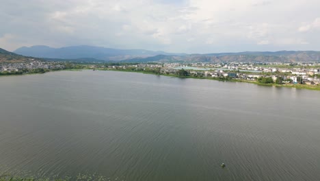 The-footage-reveals-the-lush-greenery-of-the-Er-Hai-lakeshore,-dotted-with-traditional-Bai-architecture-across-the-water