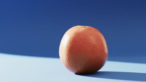 Video-of-close-up-of-orange-with-copy-space-over-blue-background