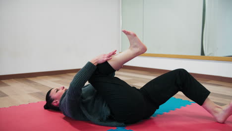 woman concentrates with stretching exercises on tatami in dance gym