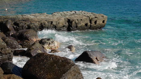 the strong sea struck a shore full of stones and pier stones leading to the water that jumped from the stone into the air and around the coast in slow motion at 120fps