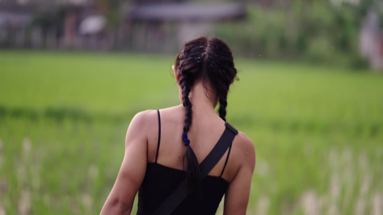 Person with braided hair walking through a green field