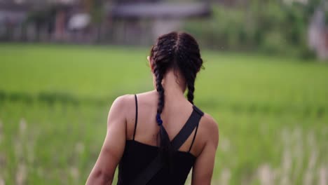 person with braided hair walking through a green field