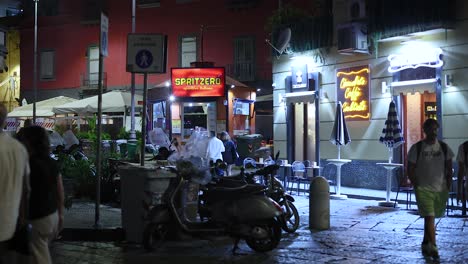 people walking by a lit street cafe