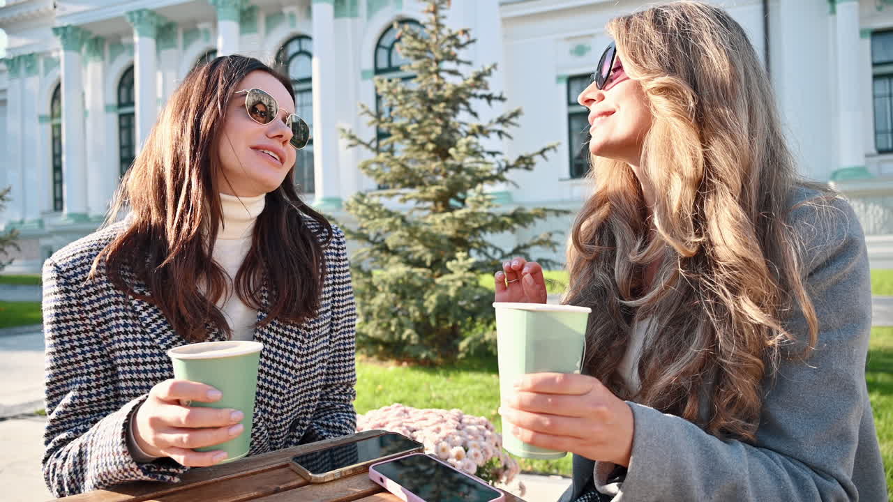 Two women talking and drinking coffee at a terrace