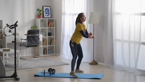 teenager girl is training alone in living room doing aerobics and gymnastics at morning keeping fit workout and sport activity