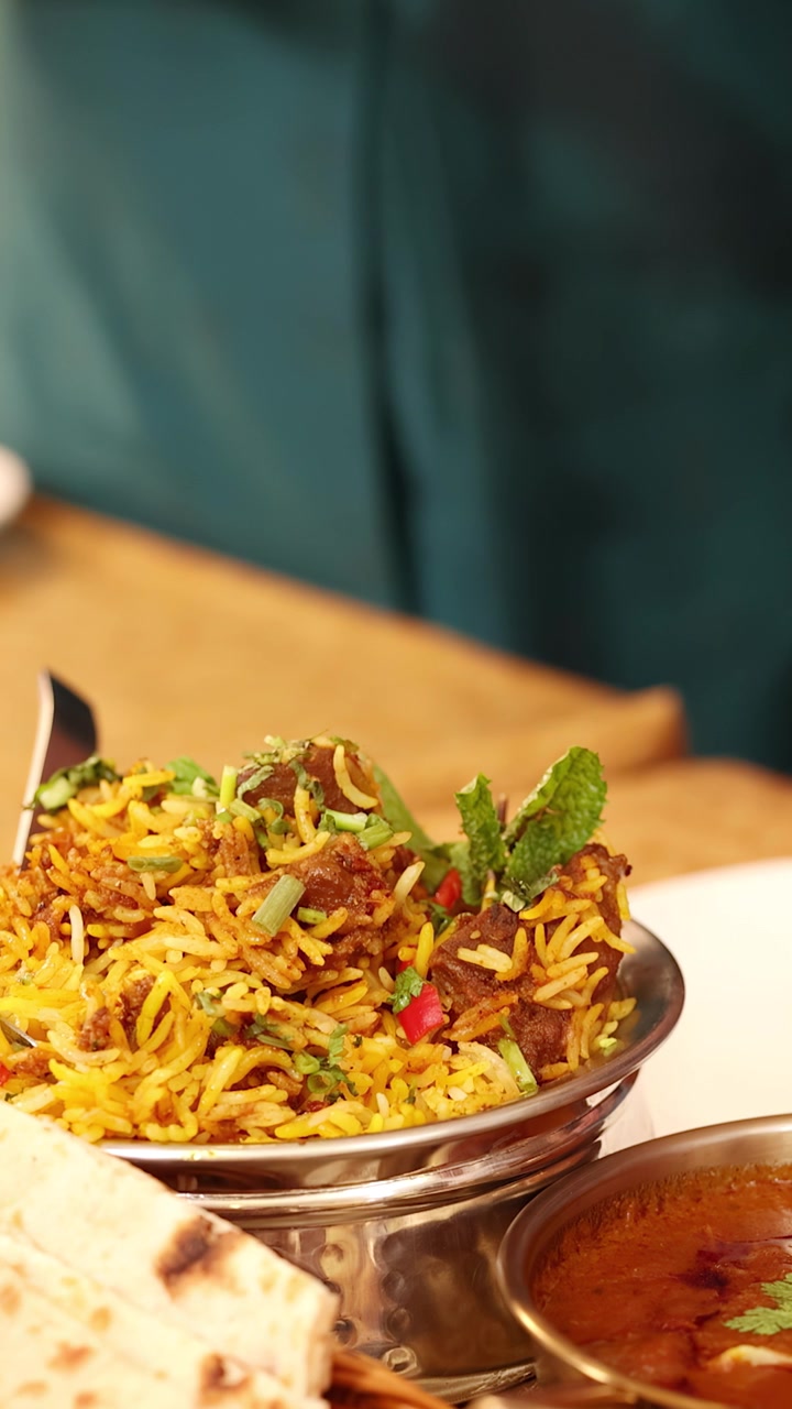 Primer plano de aromático arroz biryani amarillo, salsa de carne picante y pan plano sobre la mesa de un restaurante