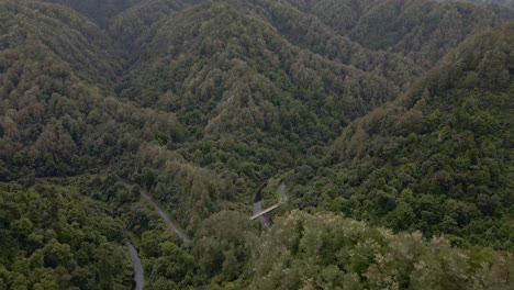 Toma-Aérea-De-Establecimiento-De-Un-Diminuto-Y-Viejo-Puente-Fluvial-Dentro-De-Una-Selva-Tropical-Montañosa-Prístina