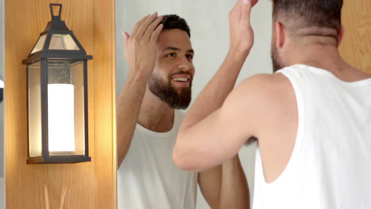 Grooming in front of mirror, man touching hair and smiling in bathroom