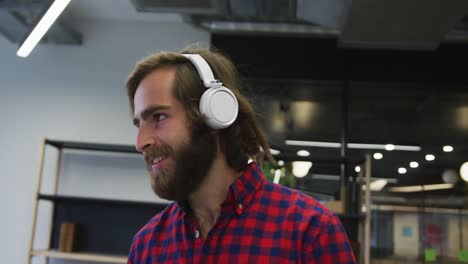 caucasian businessman walking wearing headphones dancing in a modern office