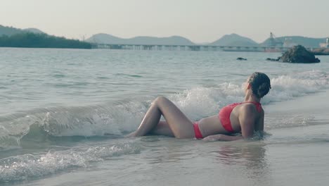 pretty lady lies on sand on surf line at resort slow motion