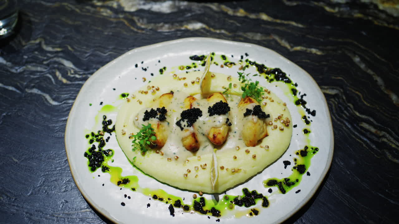 Elegant restaurant dish featuring seared seafood with creamy sauce, caviar, and microgreens served on a fine dining plate