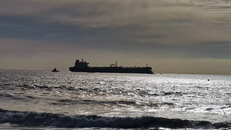 silueta de un petrolero lejos en el mar con un barco de remolque
