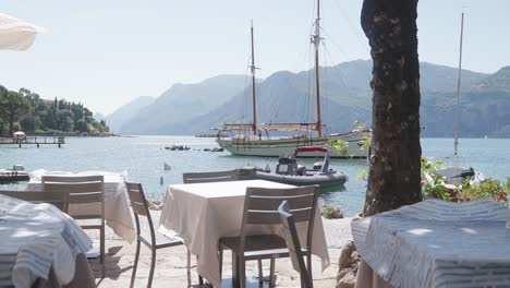 view from empty lakeside restaurant tables to anchored yacht offshore