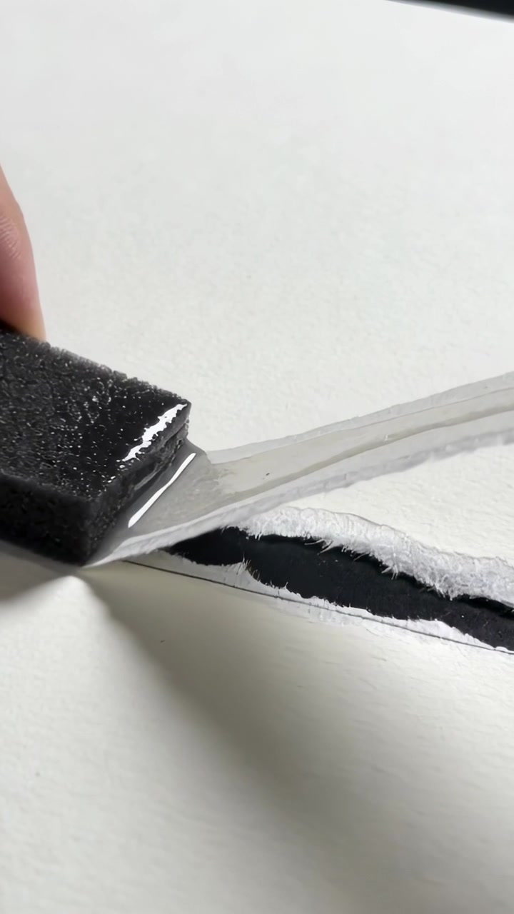 Vertical video: Contacting seam, hand sliding blade along paper tear on table, exposing black layer