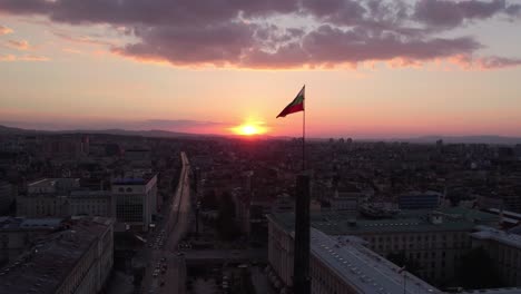 Aerial-epic-4K-shot-of-the-flag-of-Bulgaria-waving-at-sunset-with-Sofia-city-behind