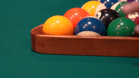 Person-Shakes-and-Tightens-Pool-Balls-on-8-Ball-Triangle-Rack-with-Hands-Closeup-on-the-Spot-with-Solid-and-Stripped-Billiard-Balls-on-Table-with-Blue-Felt-or-Cloth-and-Lifts-Wooden-Triangle