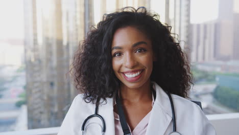 portrait of smiling female doctor wearing white coat with stethoscope in hospital office
