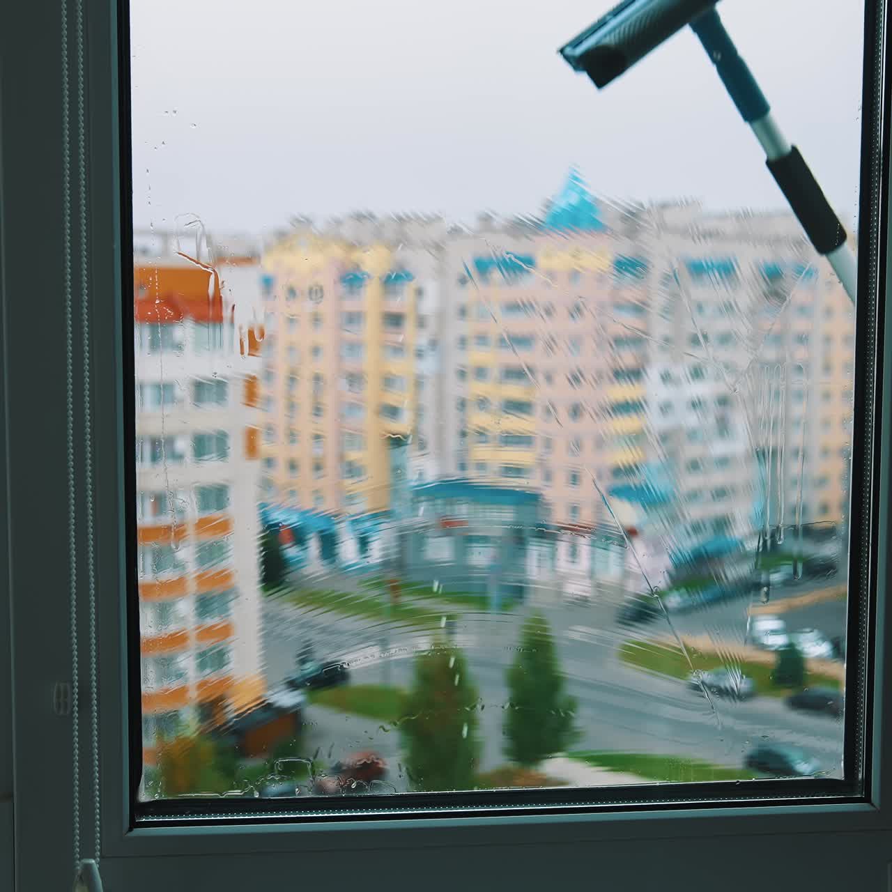 Window cleaner working with wet glass window. Close up view of cleaning window