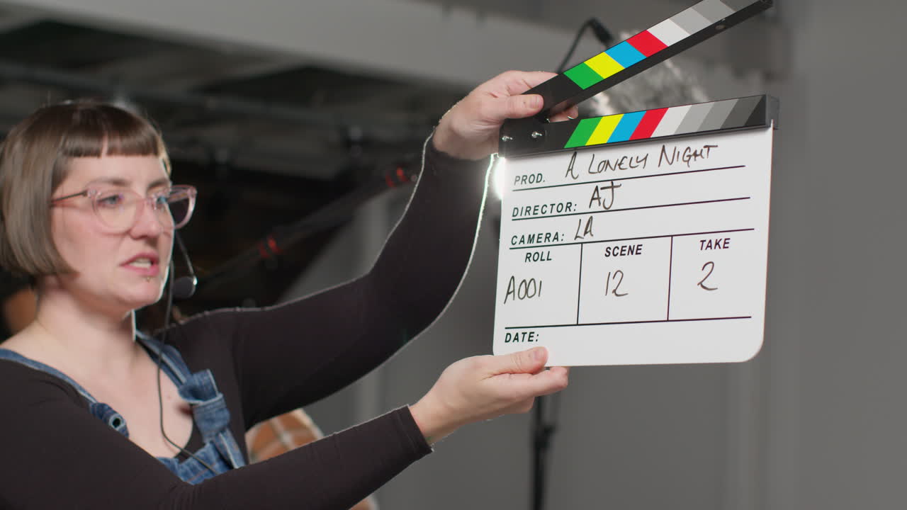 asistente femenina en el set de la película en el estudio usando clapperboard o pizarra en la película o video como actores comienzan la escena 2