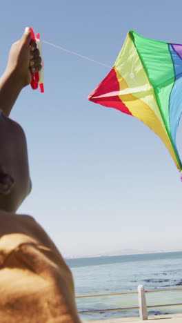 video of happy african american boy having fun with kite, running on beach