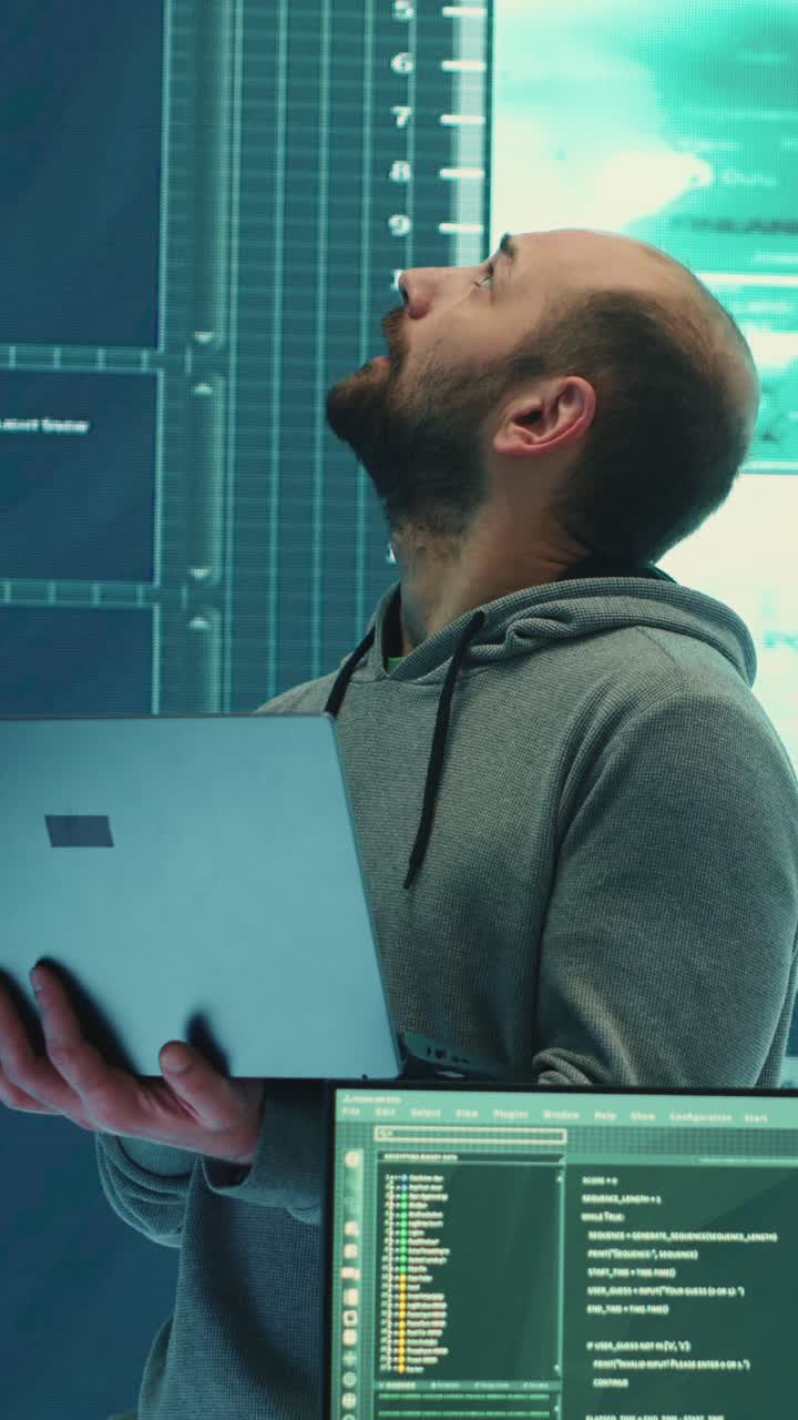 Stressed Hacker Working on Laptop in Dark High-Tech Room