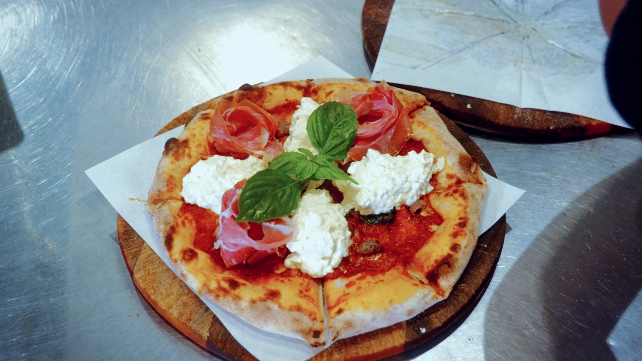 Autentico processo di preparazione della pizza in una pizzeria tradizionale italiana, con lo chef che aggiunge i condimenti sulla pizza