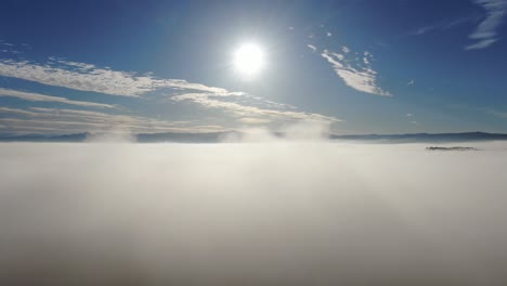 aerial flight by drone over a foggy landscape on a beautiful blue sky sunny day with mottled clouds