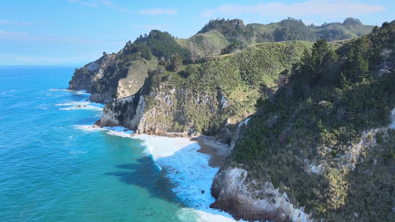 Ampia ripresa aerea discendente con drone su una piccola spiaggia isolata sulla costa della Nuova Zelanda. 4k 59.94p.