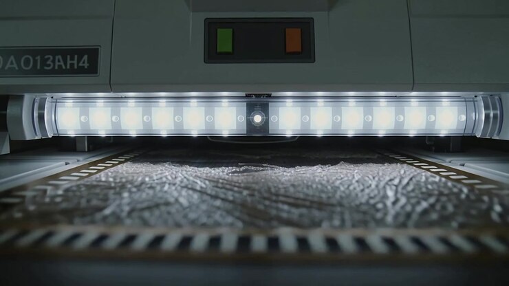 Feeding machine front conveying textured sheet along platen, LED array lighting at inspection bay
