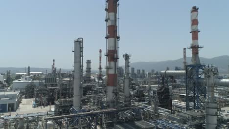 aerial footage of a large scale oil refinery with smoke stacks and petroleum storage tanks