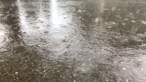 slow motion of heavy rain drops falling on concrete street and bouncing off