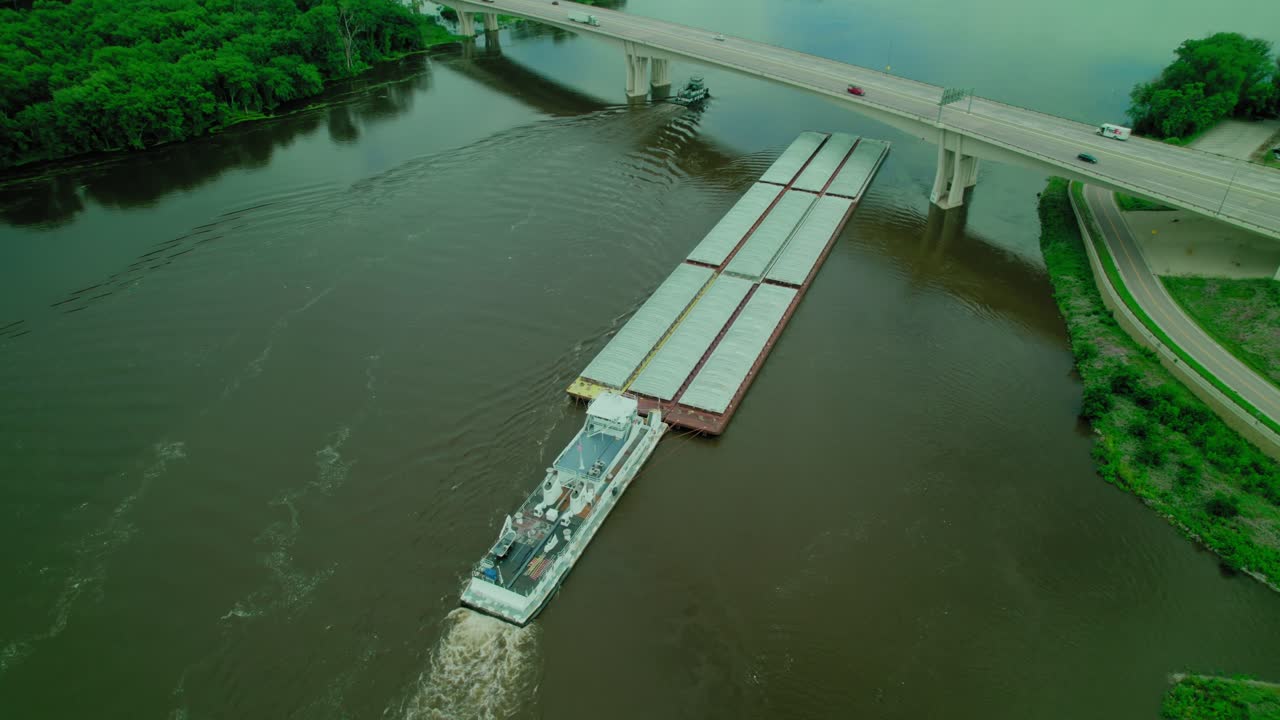 Tugboat pushing barge floating on missisipi river in wisconsin under Dresbach Bridge