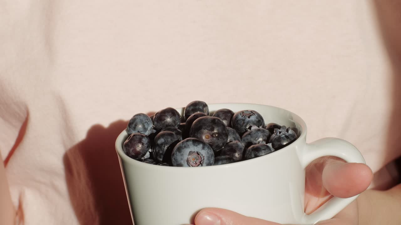 Woman eating blueberries from a cup